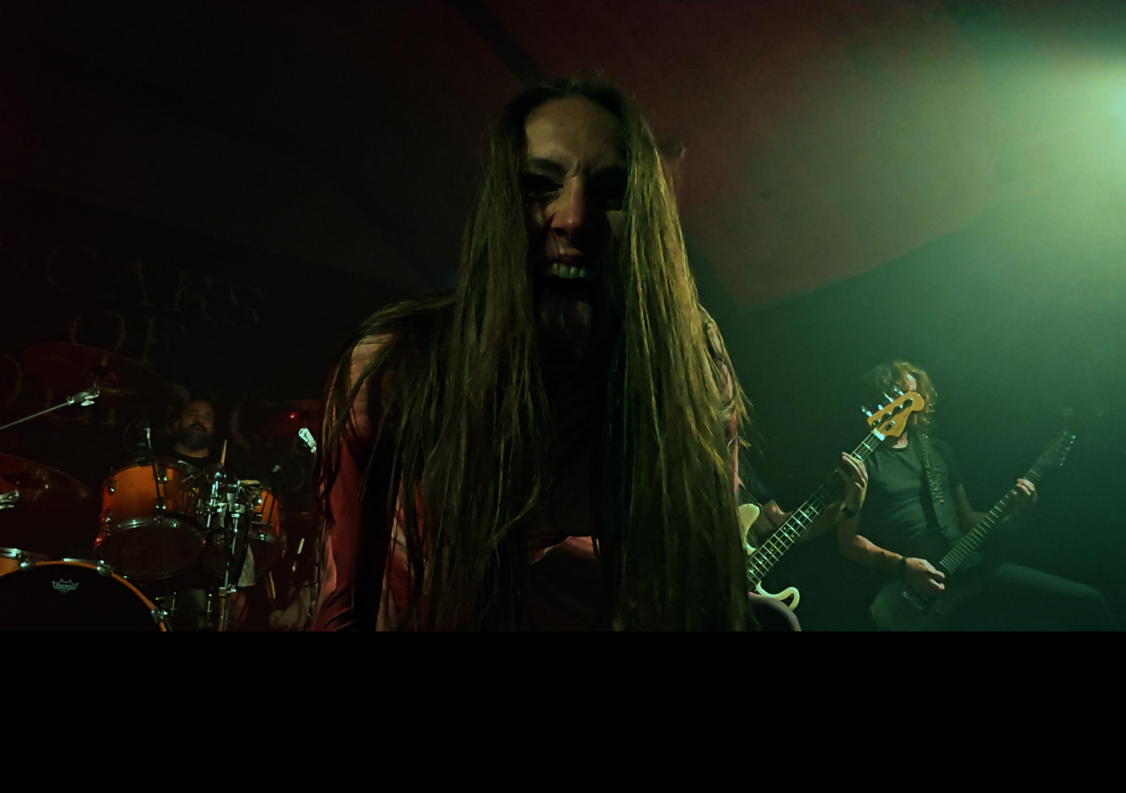 Live-Act auf der Bühne mit dramatischem Grünlicht, im Hintergrund Banner „Scars of …“